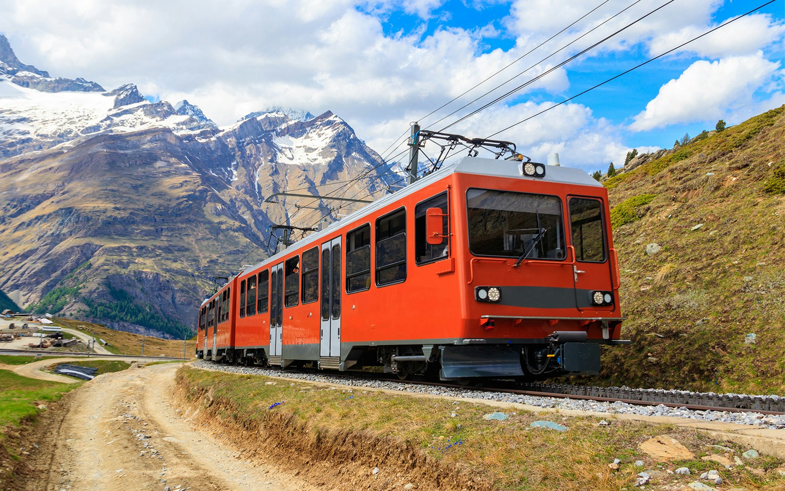 Gornergrat Railway train traveling through snowy Swiss Alps with Matterhorn in the background.