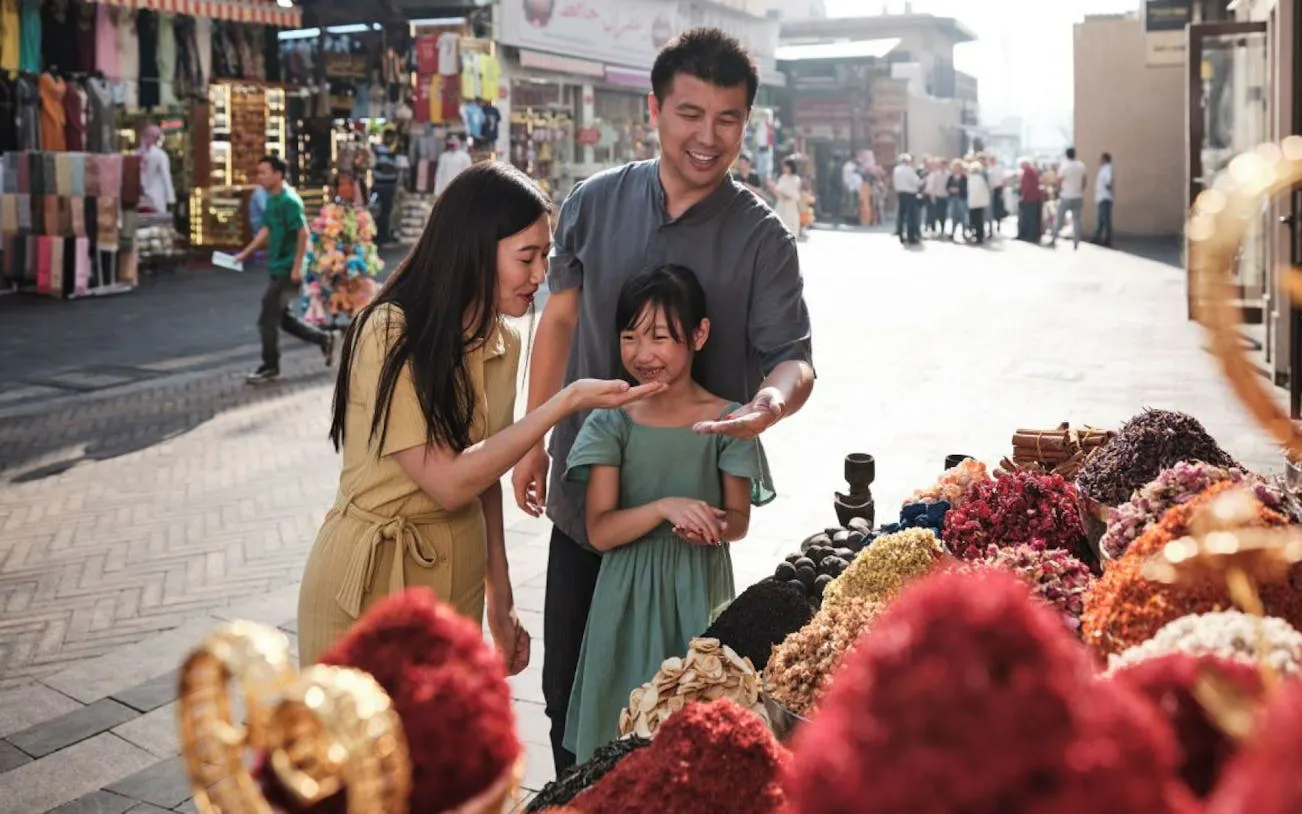 Family exploring spice market during Dubai Traditional Trolley Tour with Emirati storytellers.