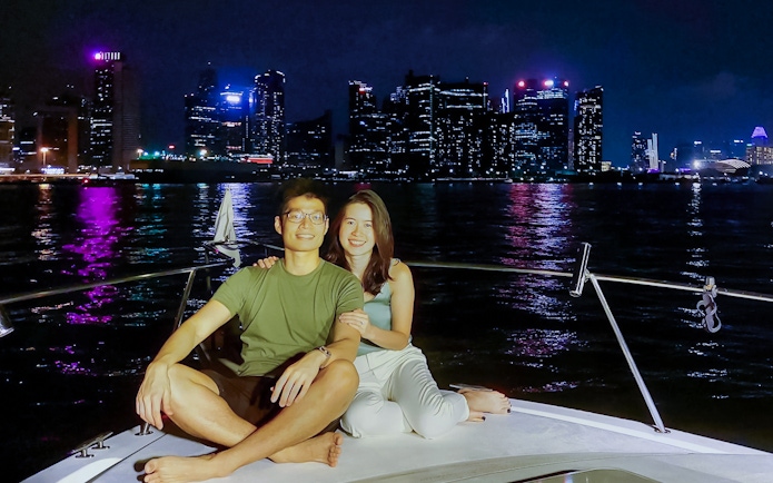 Couple enjoying a yacht cruise with Marina Bay Sands skyline in the background.