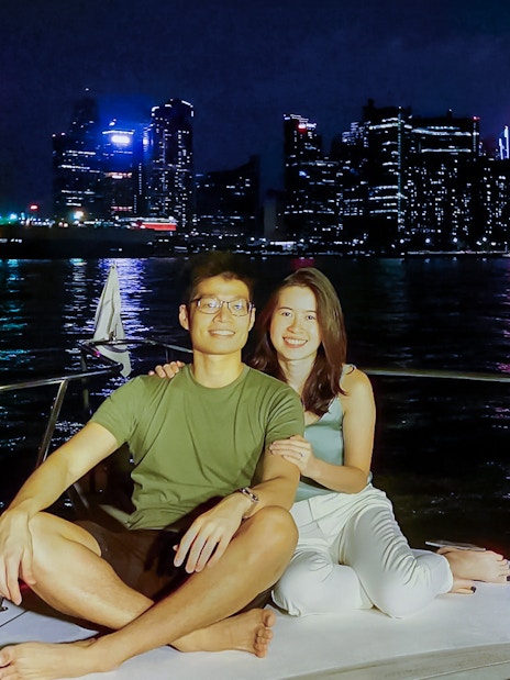 Couple enjoying a yacht cruise with Marina Bay Sands skyline in the background.