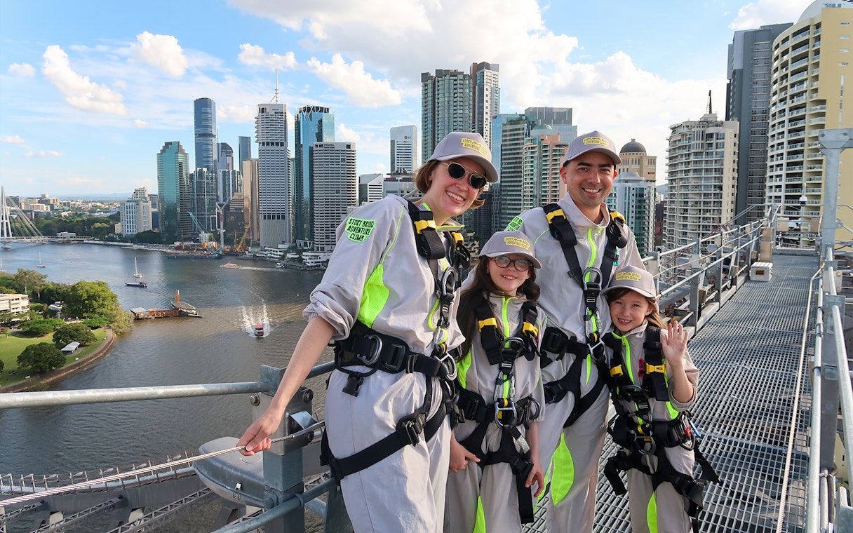 Family in harnesses on Story Bridge Adventure Climb, Brisbane skyline in background.