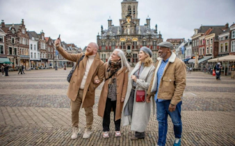 Tourists taking a selfie in Delft's historic market square during a guided day tour from Brussels.