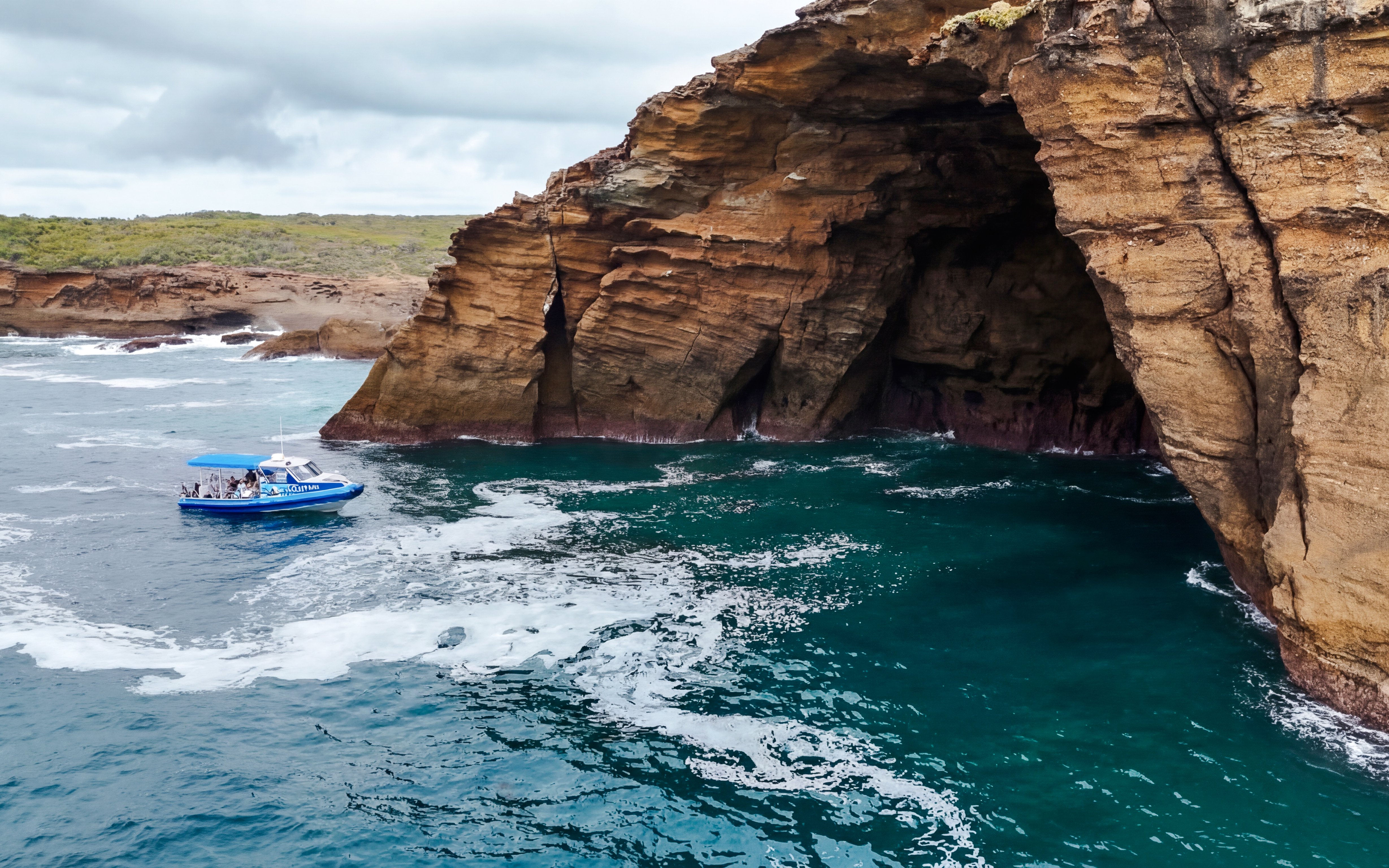 Boat near rocky cliffs on Lake Macquarie Coastal Boat Tour.