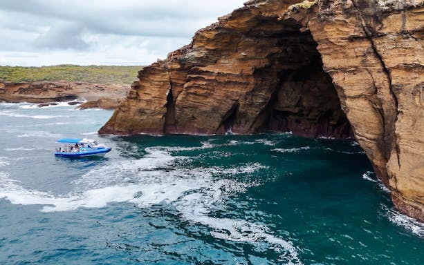 Boat near rocky cliffs on Lake Macquarie Coastal Boat Tour.