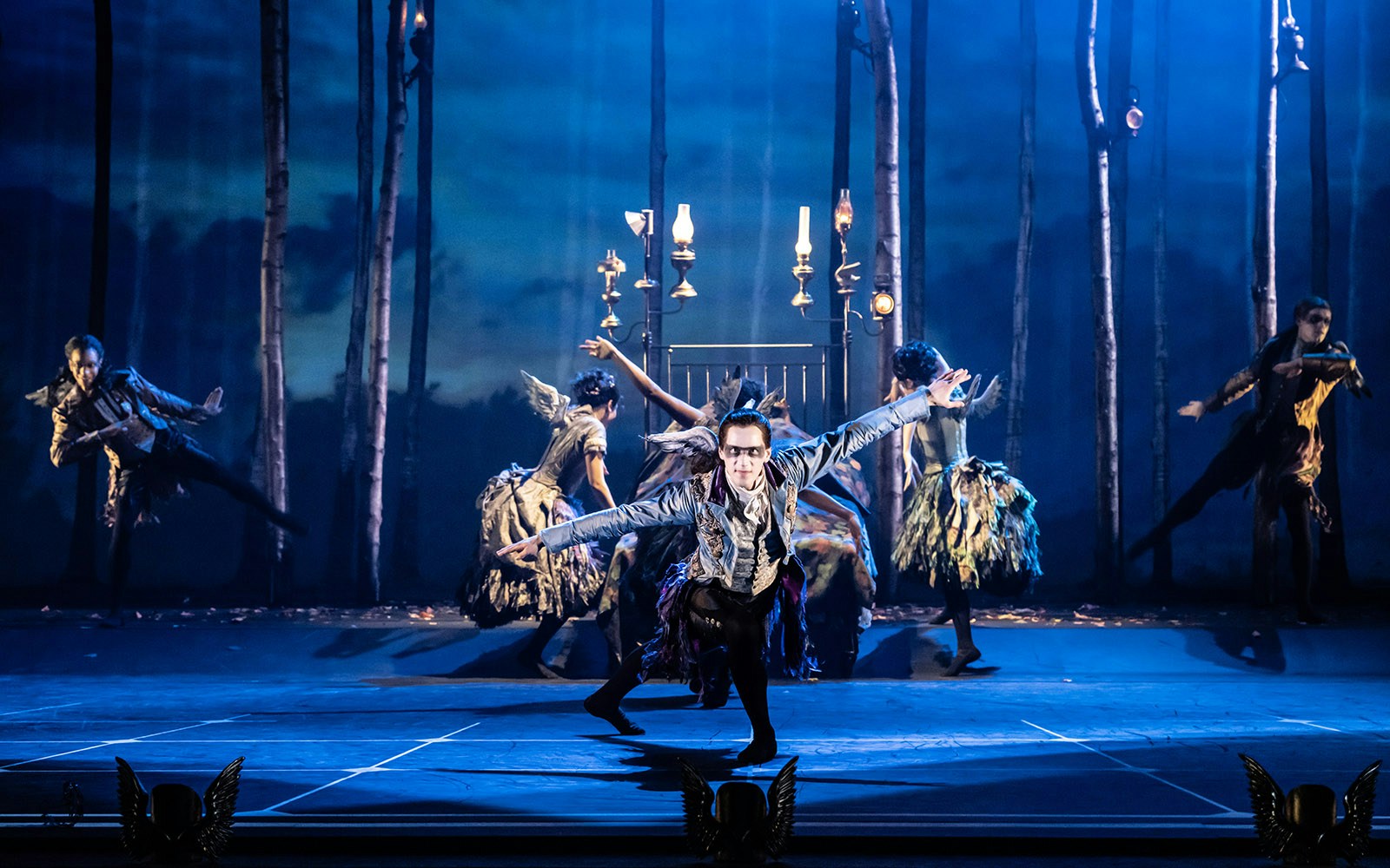 Dancers performing in Matthew Bourne's Sleeping Beauty with a forest backdrop.