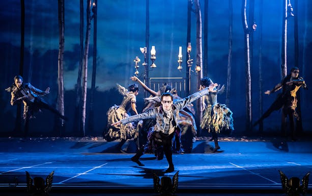 Dancers performing in Matthew Bourne's Sleeping Beauty with a forest backdrop.