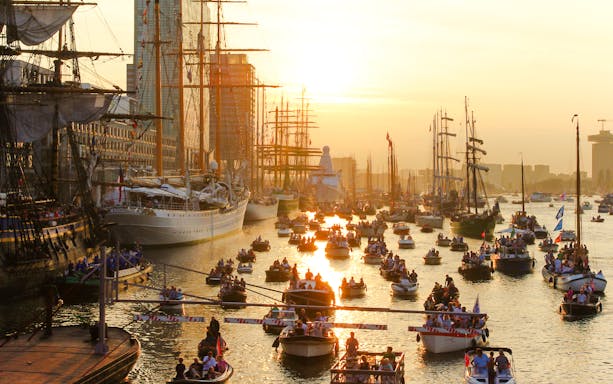 Boats and tall ships on the water during SAIL Amsterdam evening event.