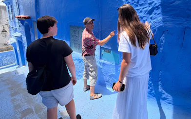 Guide explaining blue walls to tourists in Chefchaouen, Morocco.