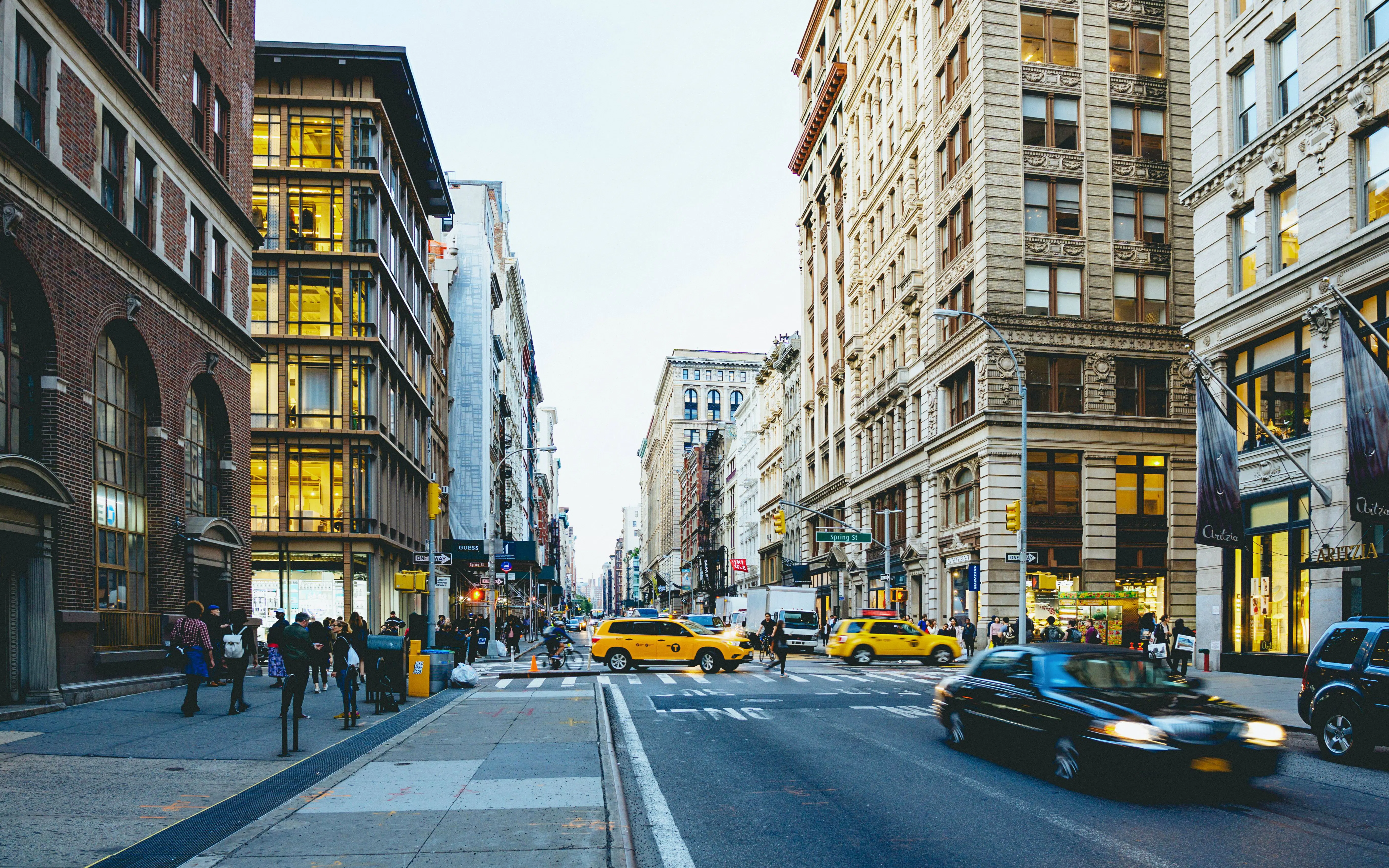 Busy street scene in SoHo, New York City with yellow taxis and historic buildings.