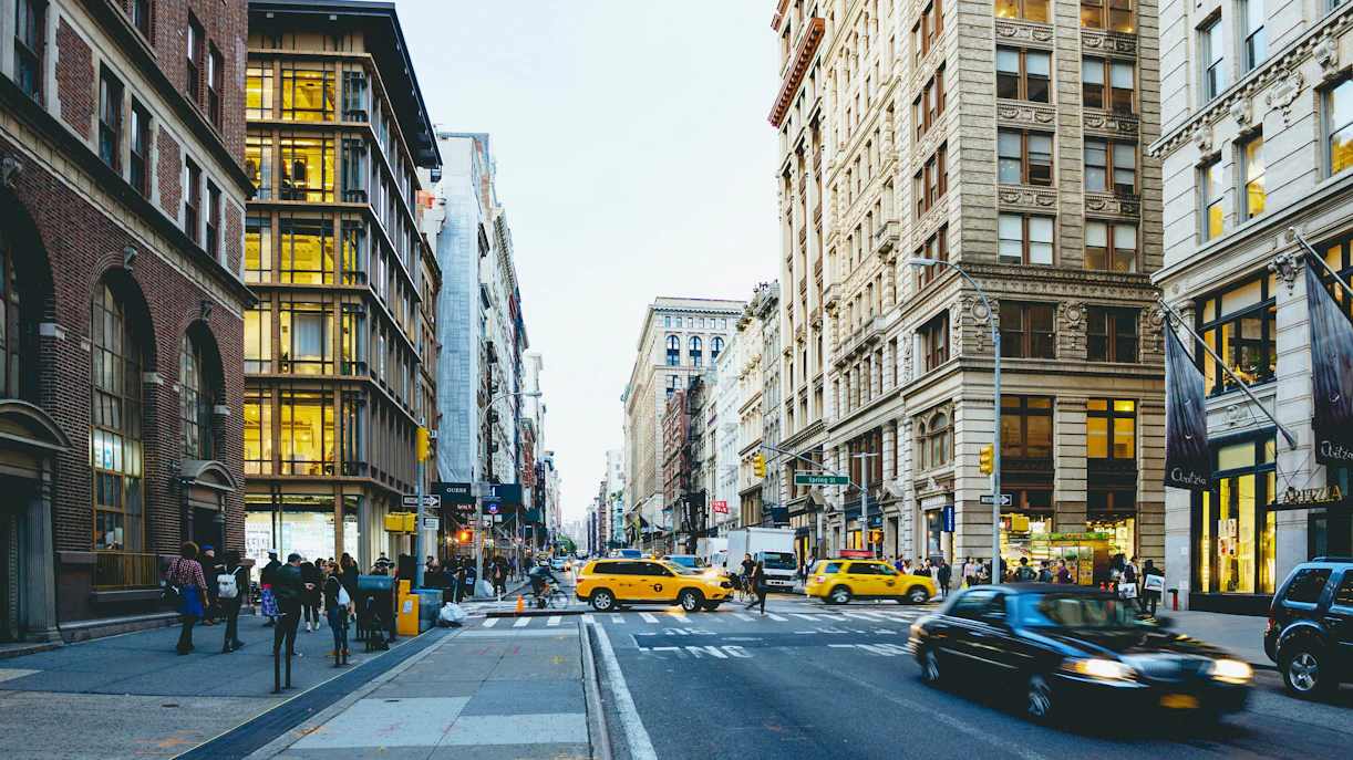 Busy street scene in SoHo, New York City with yellow taxis and historic buildings.