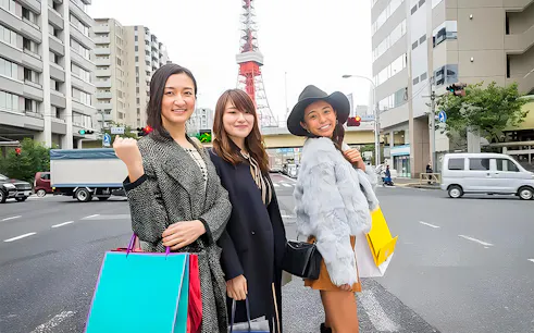 Tokyo Tower in background with three people shopping on a city street.