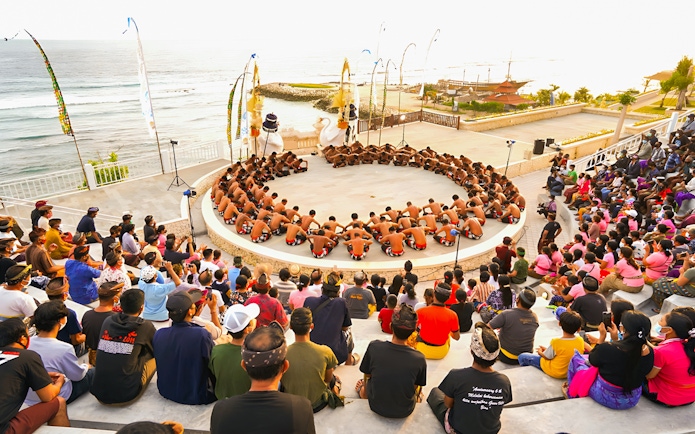 Kecak and Fire Dance performance at Melasti Beach amphitheater with ocean view.