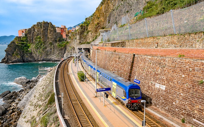 Train at Manarola station with coastal cliffs in Cinque Terre, Italy.