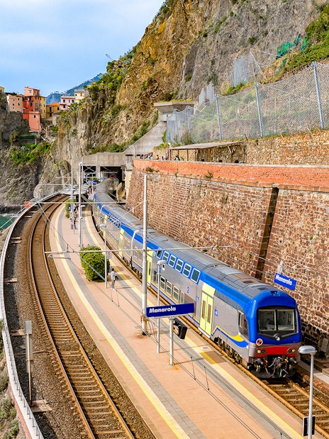 Train at Manarola station with coastal cliffs in Cinque Terre, Italy.