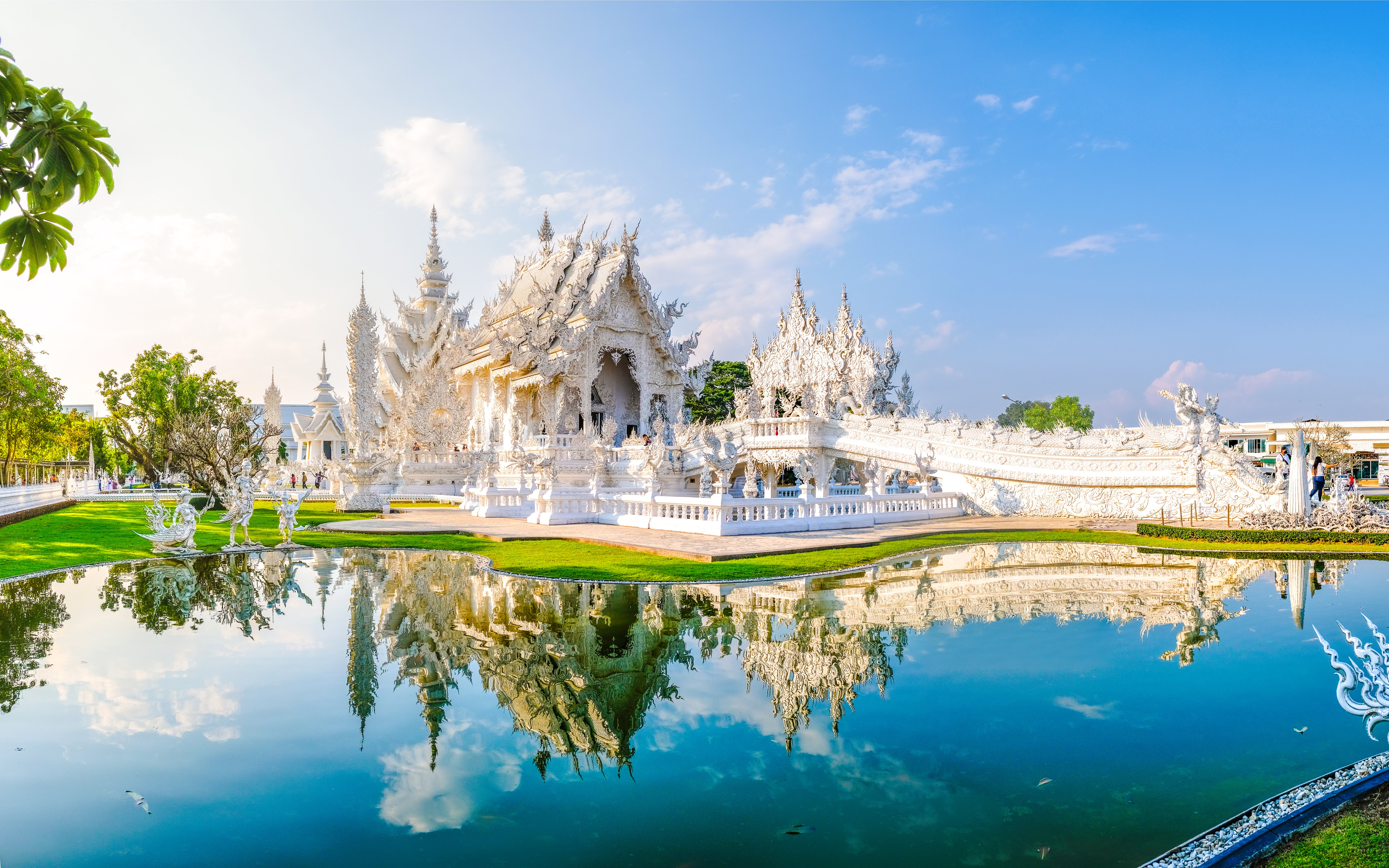 Wat Rong Khun, White Temple in Chiang Rai, Thailand, reflecting in a pond.