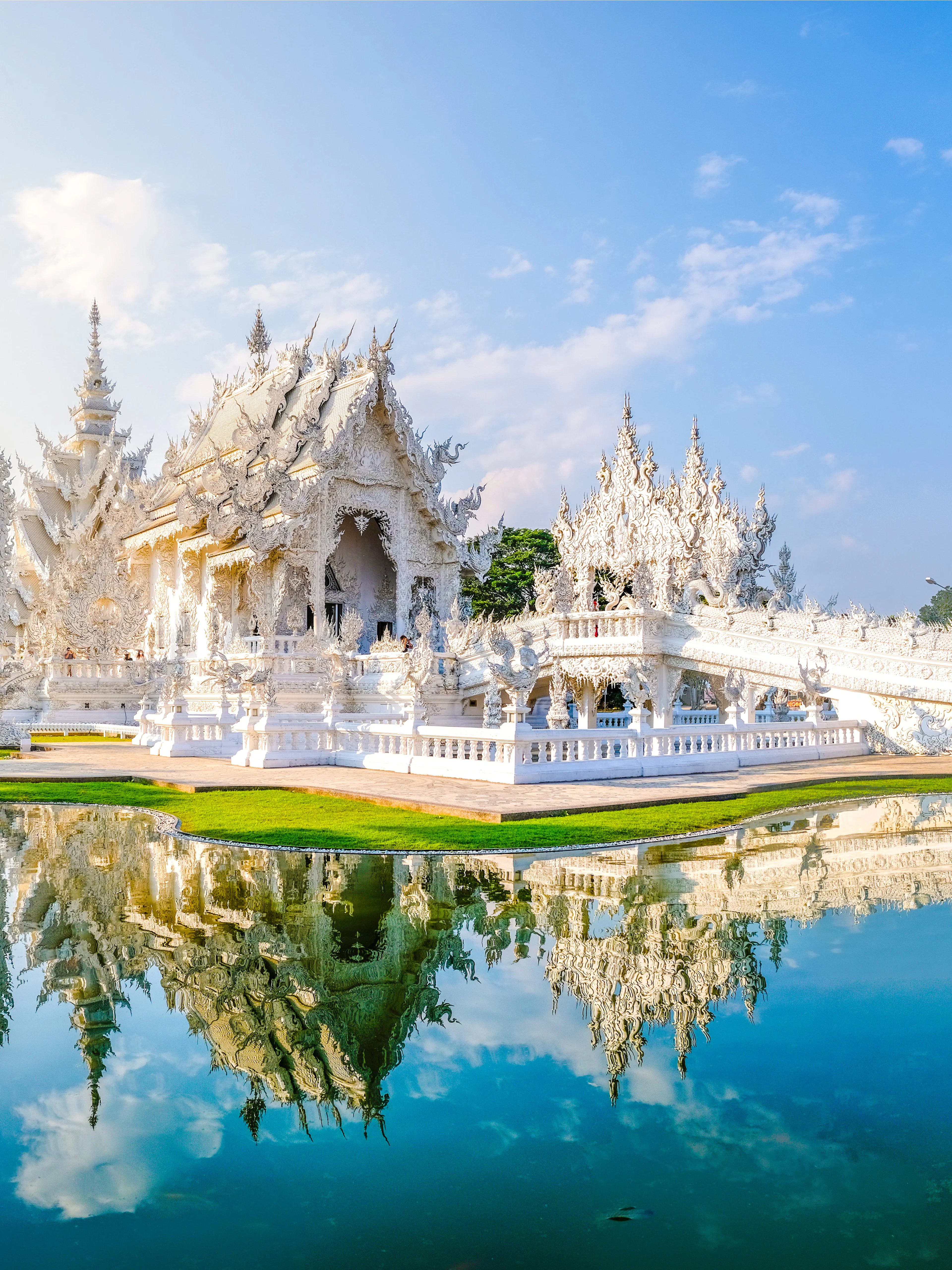 Wat Rong Khun, White Temple in Chiang Rai, Thailand, reflecting in a pond.