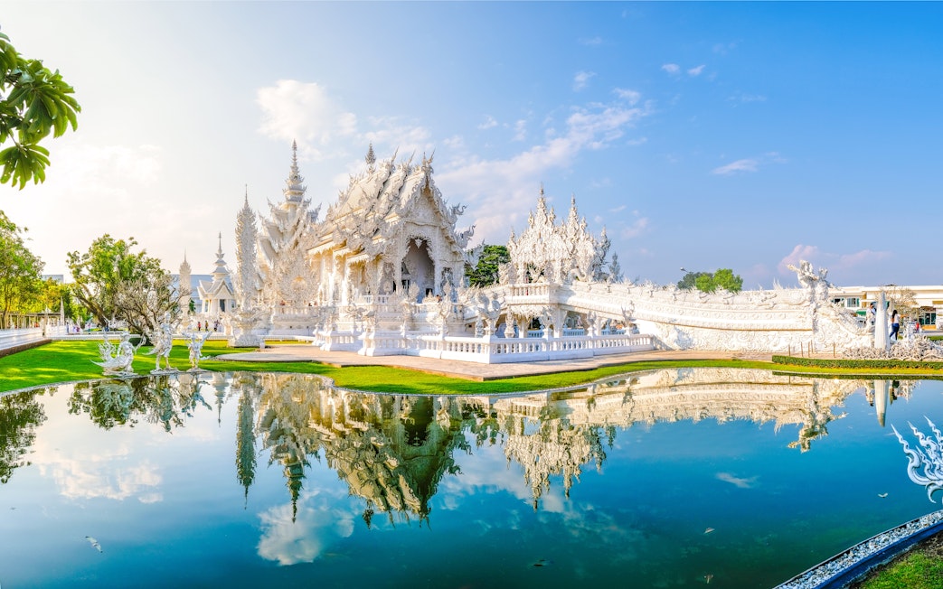 Wat Rong Khun, White Temple in Chiang Rai, Thailand, reflecting in a pond.