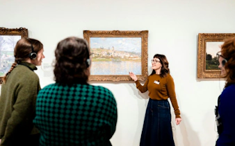 Tour guide explaining artwork to visitors at National Gallery of Victoria.