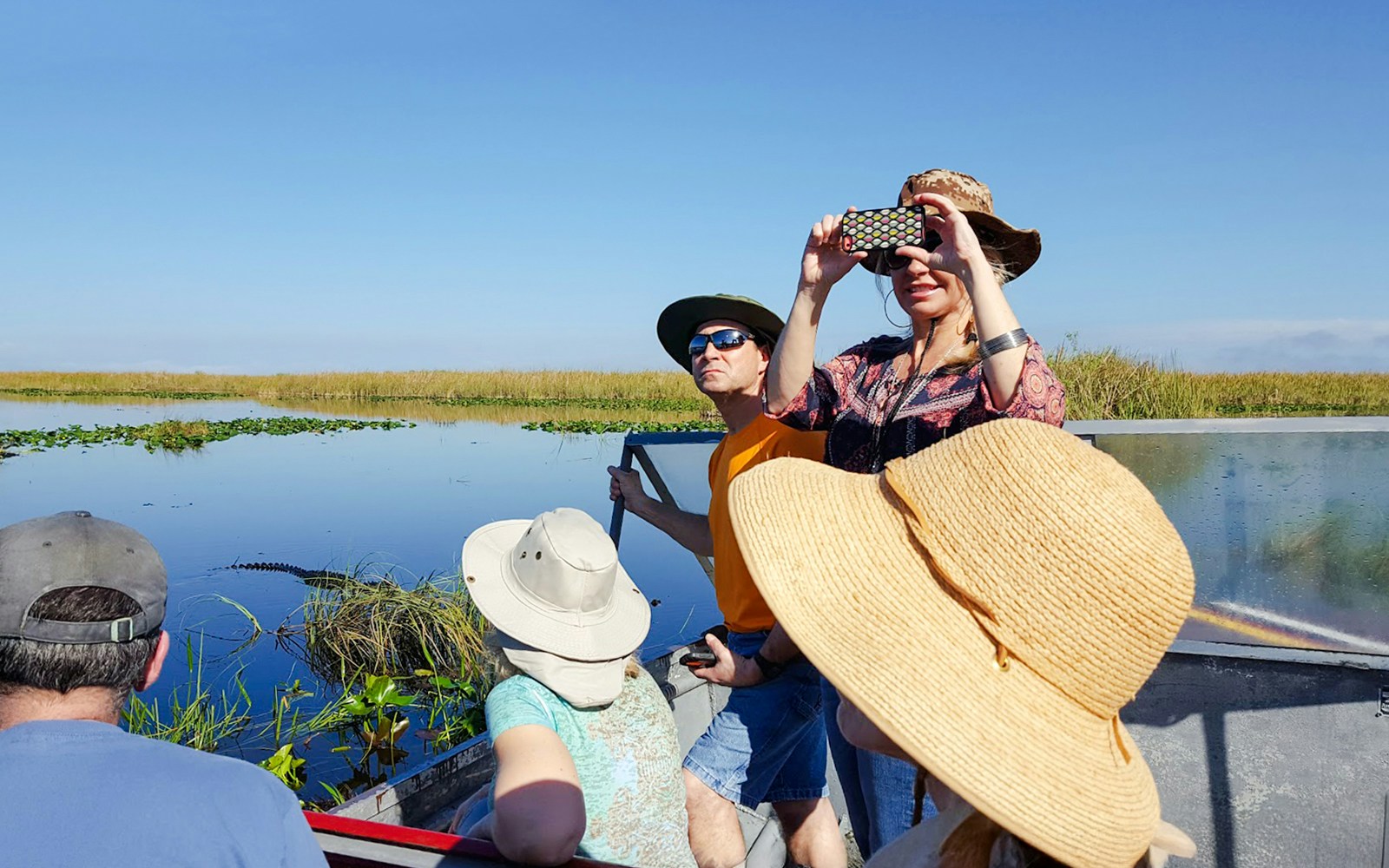 Guests photographing scenery on airboat during National Park tour.
