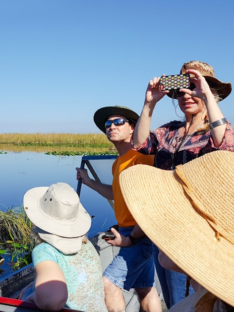 Guests photographing scenery on airboat during National Park tour.
