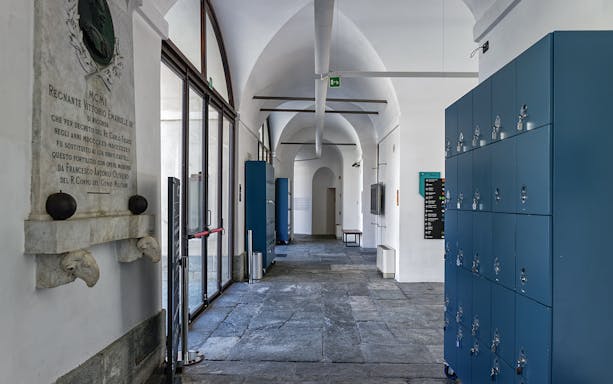 Fortress of Bard corridor with historical plaque and lockers, part of guided tour with lunch.