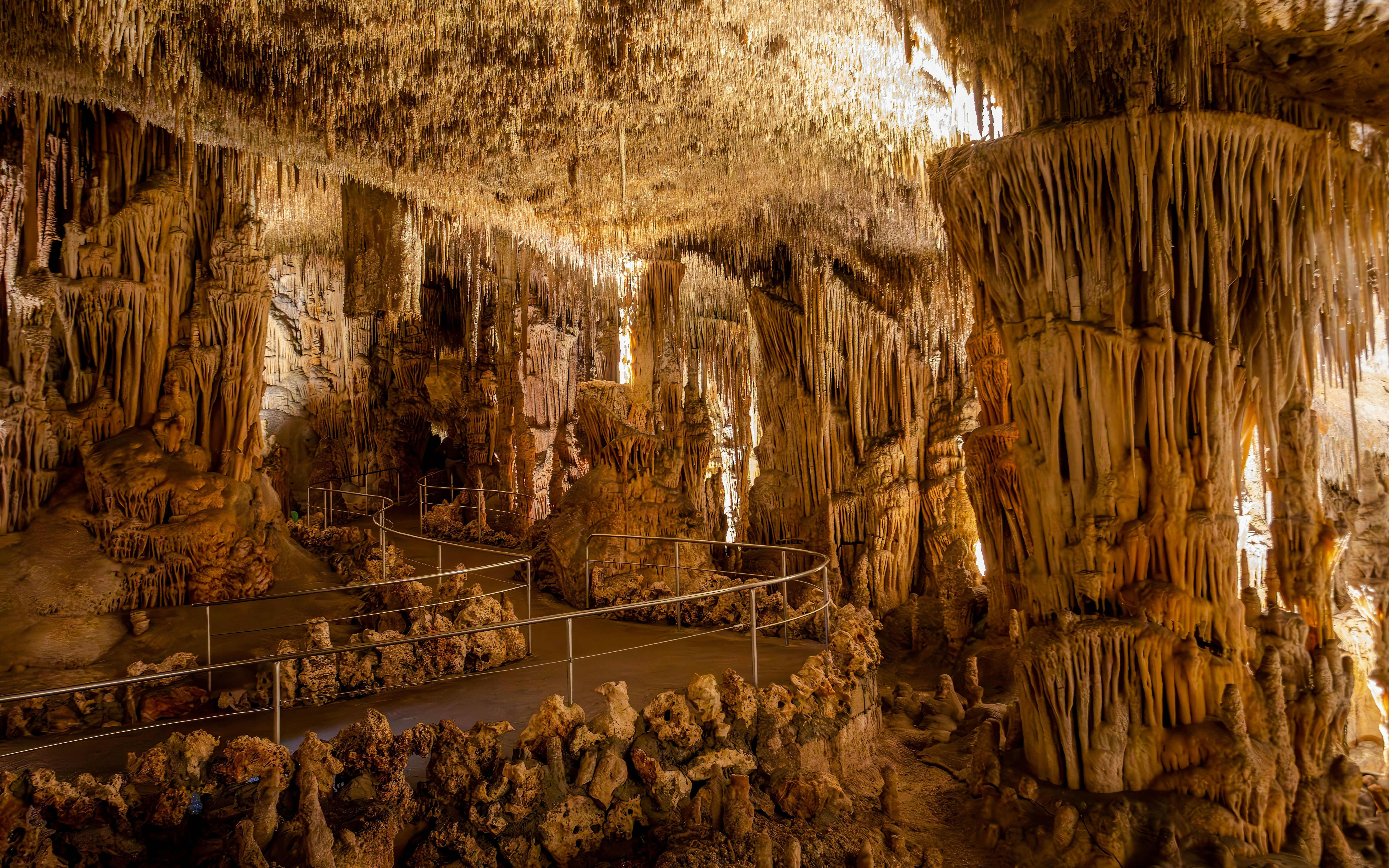 Stalactites and stalagmites in Drach Caves, Mallorca, with a walkway through the formations.