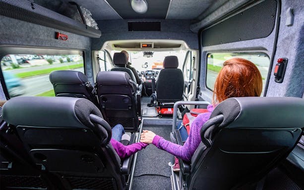 Mother and child holding hands in a tour van.