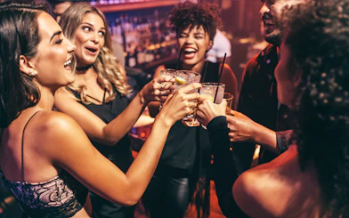 Friends toasting with drinks at a lively club.
