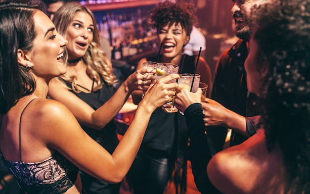 Friends toasting with drinks at a lively club.