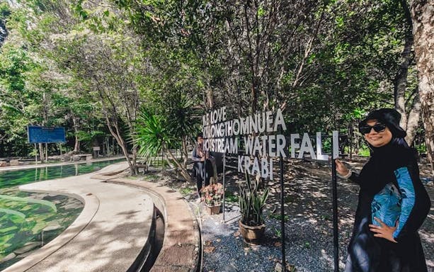 KhongThomNuea Hot Stream Waterfall sign in Krabi, Thailand, surrounded by lush greenery.