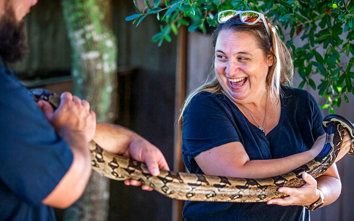 Person holding a large snake at Everglades reptile exhibit.