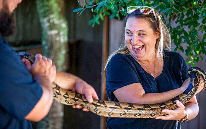 Person holding a large snake at Everglades reptile exhibit.