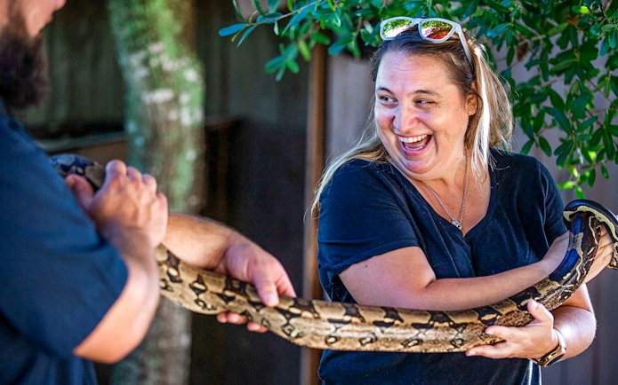 Person holding a large snake at Everglades reptile exhibit.