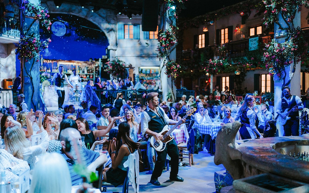 Guests enjoying live music at Mamma Mia! The Party in a vibrant Greek taverna setting.