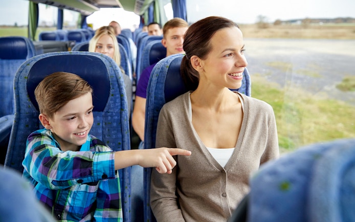 Woman and child smiling on a bus tour, looking out the window.