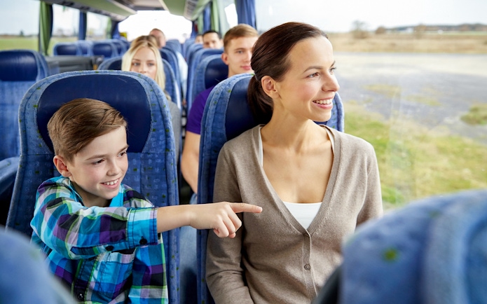 Woman and child smiling on a bus tour, looking out the window.