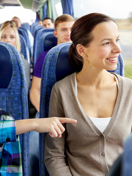 Woman and child smiling on a bus tour, looking out the window.