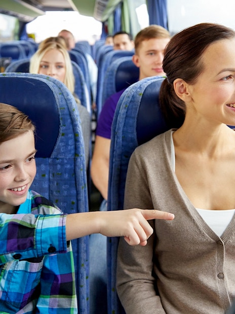 Woman and child smiling on a bus tour, looking out the window.