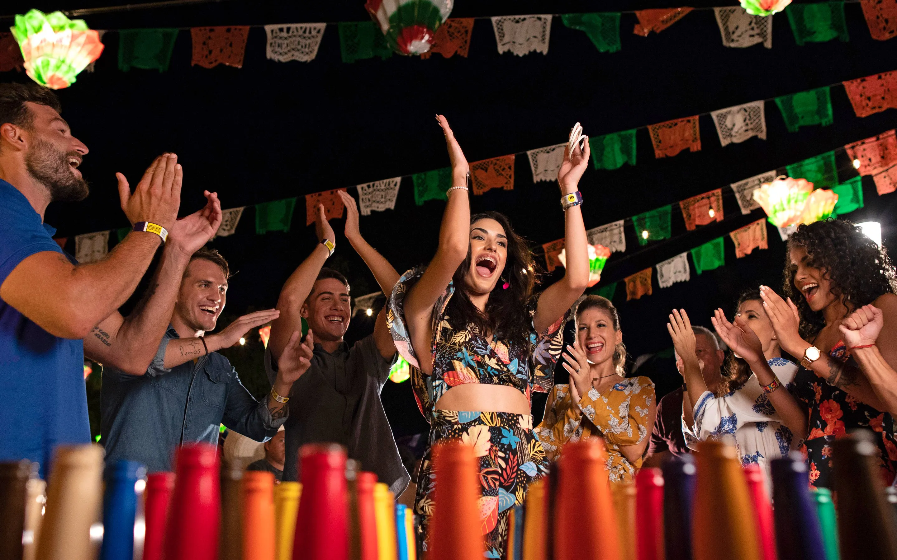 Guests enjoying a festive night at Xoximilco Park with colorful decorations and lively atmosphere.