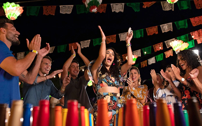 Guests enjoying a festive night at Xoximilco Park with colorful decorations and lively atmosphere.
