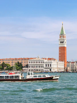 Venice water bus cruising by St. Mark's Campanile and historic buildings.