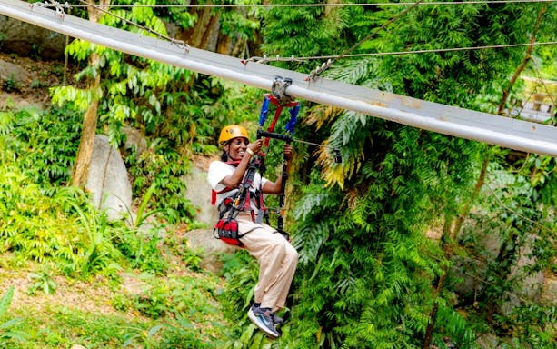 Ziplining through lush forest at SKY ROCK eco-adventure, Thailand.