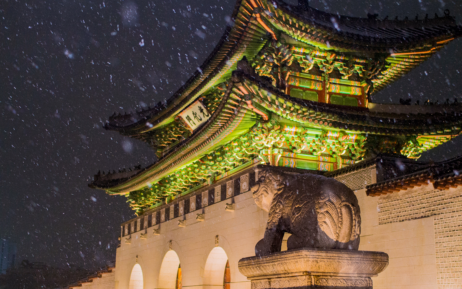 Gyeongbokgung Palace at night with illuminated gate and stone guardian in Seoul, South Korea.