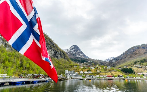Norwegian flag with Geiranger village and fjord view in Norway.
