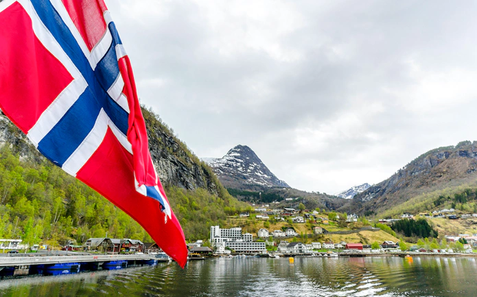 Norwegian flag with Geiranger village and fjord view in Norway.