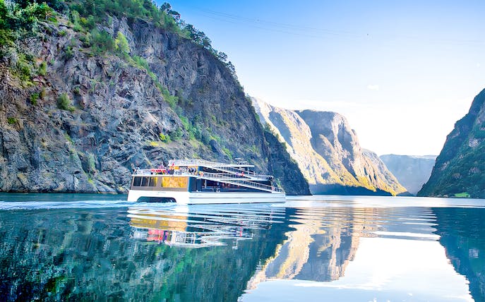 Cruise ship on Nærøyfjord surrounded by steep cliffs and calm water.