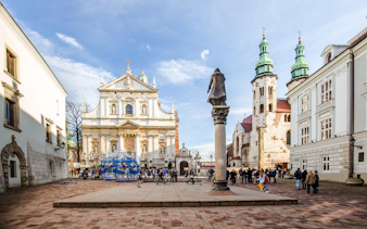 Krakow Old Town square with historic church and tourists, part of golf cart tour.