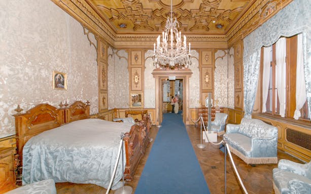 Miramare Castle bedroom with ornate bed and historical furnishings in Trieste, Italy.
