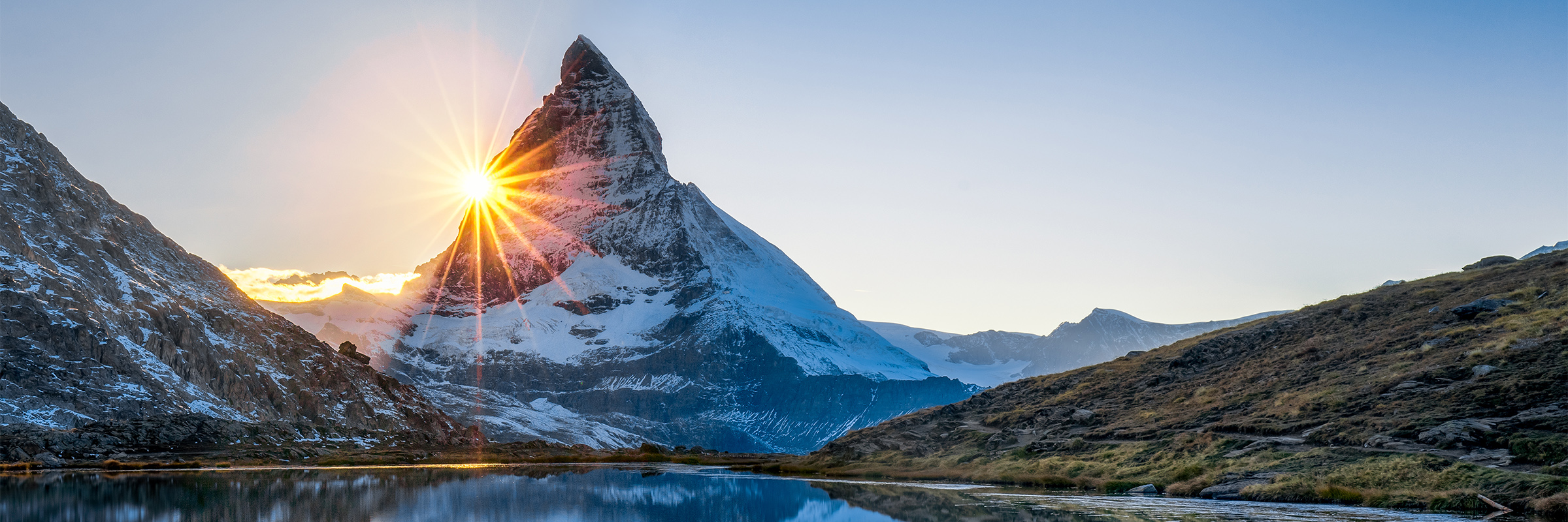 Sunrise over the Matterhorn at Glacier Paradise, Switzerland, reflecting in a tranquil lake.