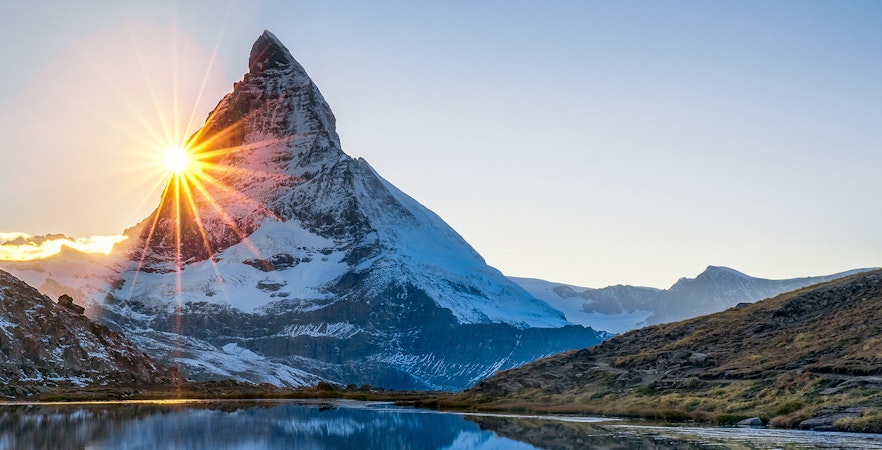 Sunrise over the Matterhorn at Glacier Paradise, Switzerland, reflecting in a tranquil lake.